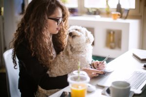 Designer working at home office and holding her puppy